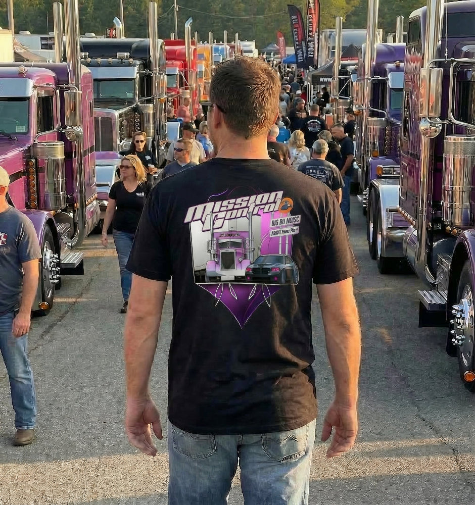 Man wearing a 'Mission Control' t-shirt at a truck show with various trucks in the background.