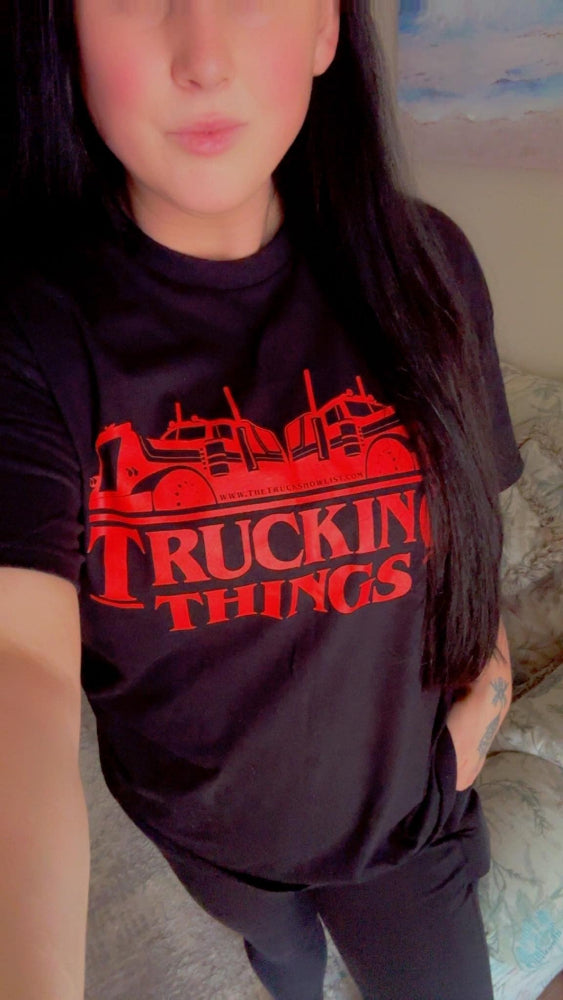 Person wearing a black t-shirt with red 'Trucking Things' text and graphics.
