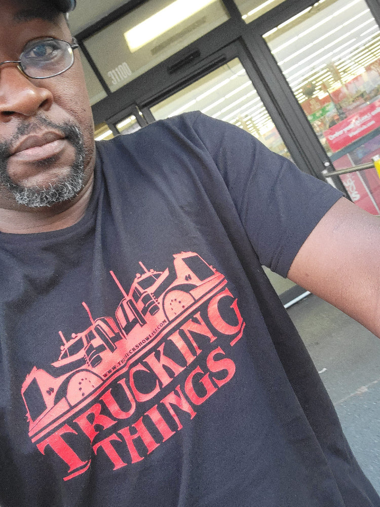 Man wearing a Trucking Things tshirt in an indoor setting.